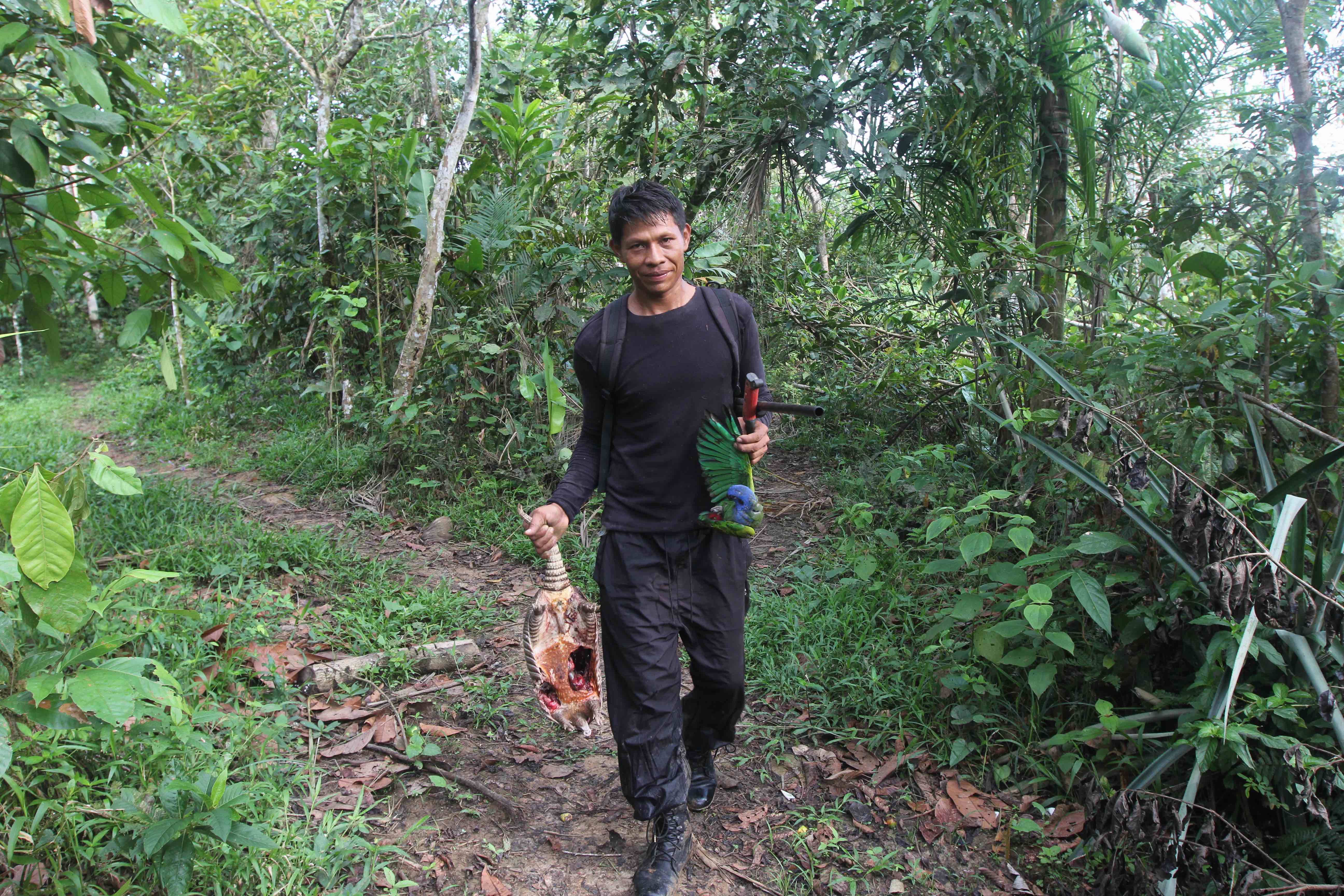 Hunter Diomedes Silva returns home from an early-morning check of his traps, carrying an armadillo and a parrot. Photo: Barbara Fraser/CIFOR.